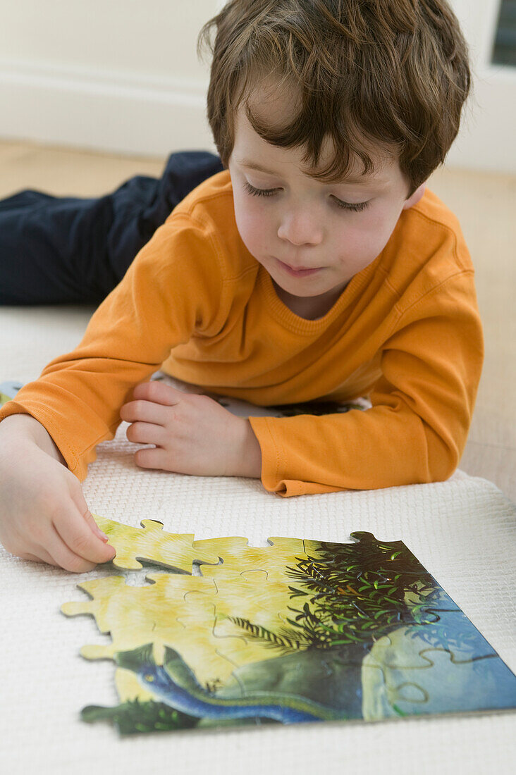 Boy lying on floor playing with jigsaw puzzle