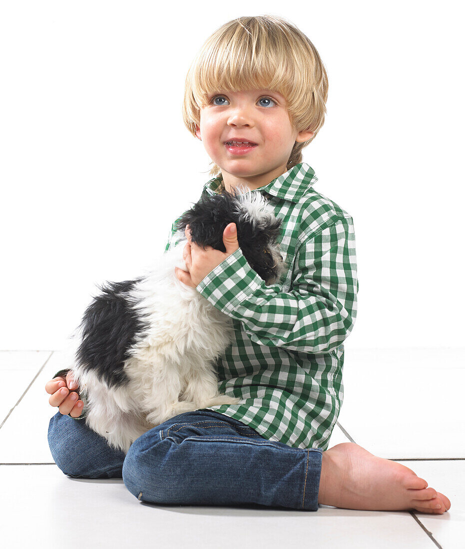 Boy sitting on floor holding a puppy