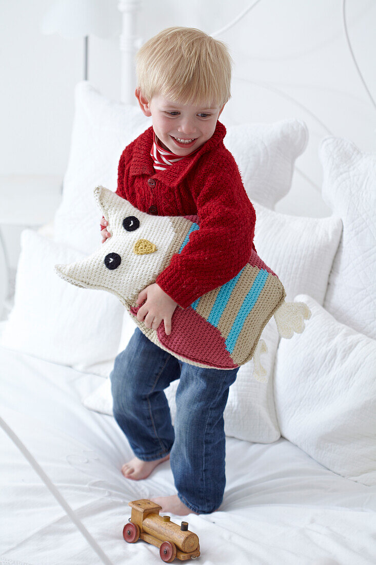 Boy holding a crocheted owl cushion