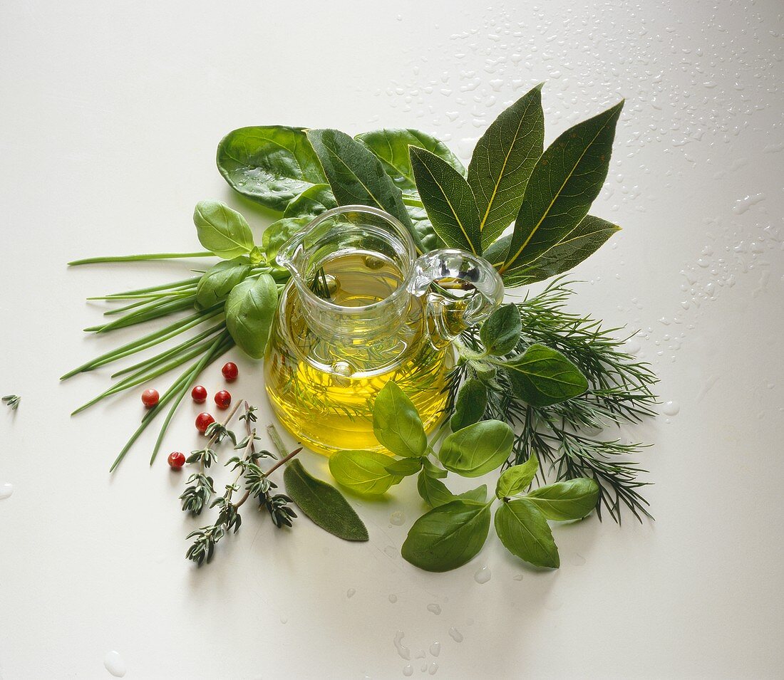 A Small Pitcher of Homemade Herbed Oil; Assorted Herbs