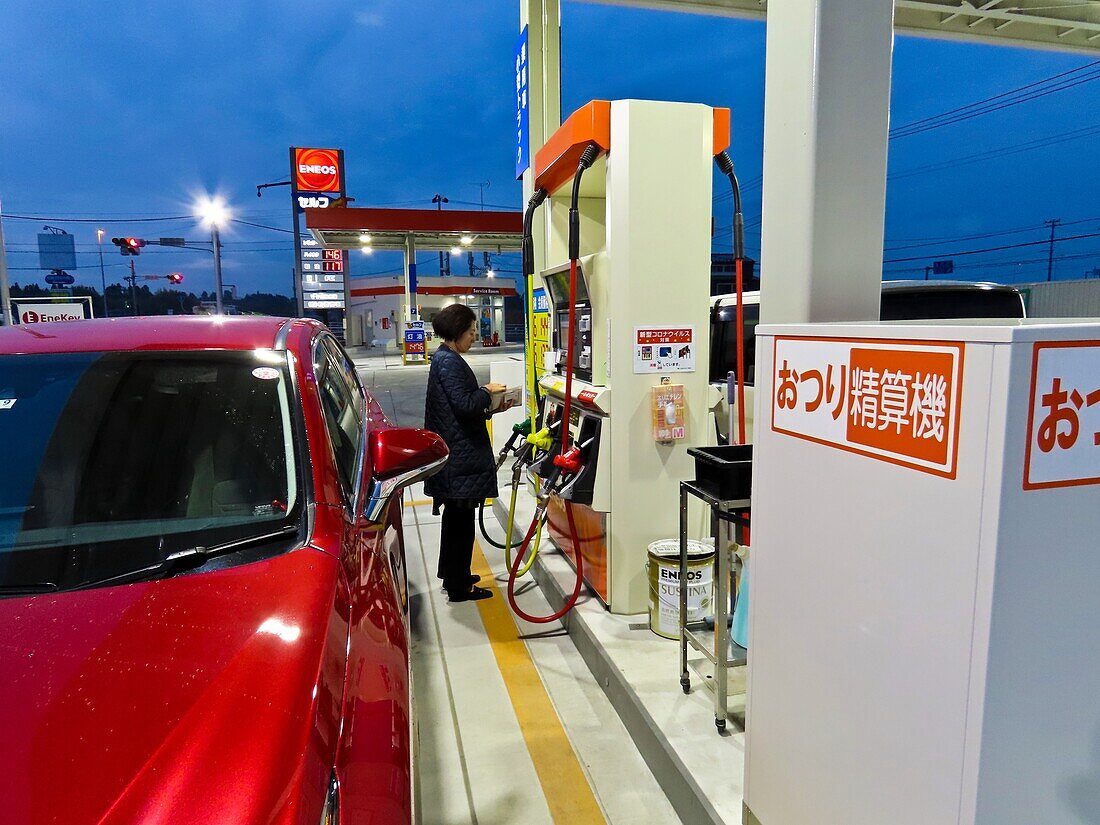 Woman using petrol pump, Japan