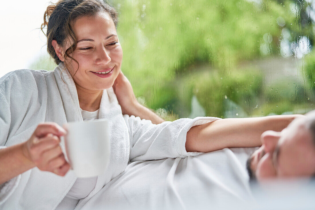 Happy couple drinking coffee and talking in bed