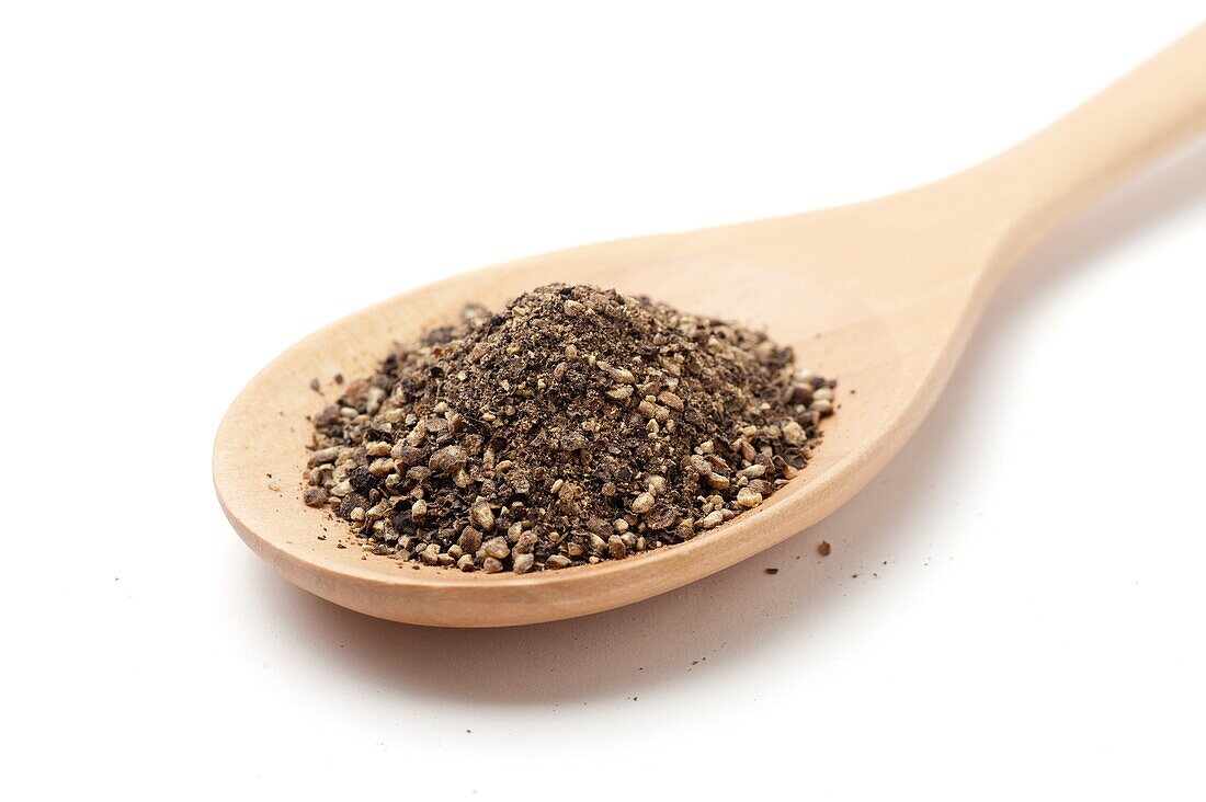 Ground black pepper on a wooden spoon