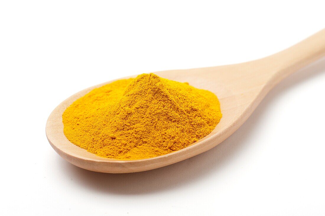Ground turmeric on a wooden spoon