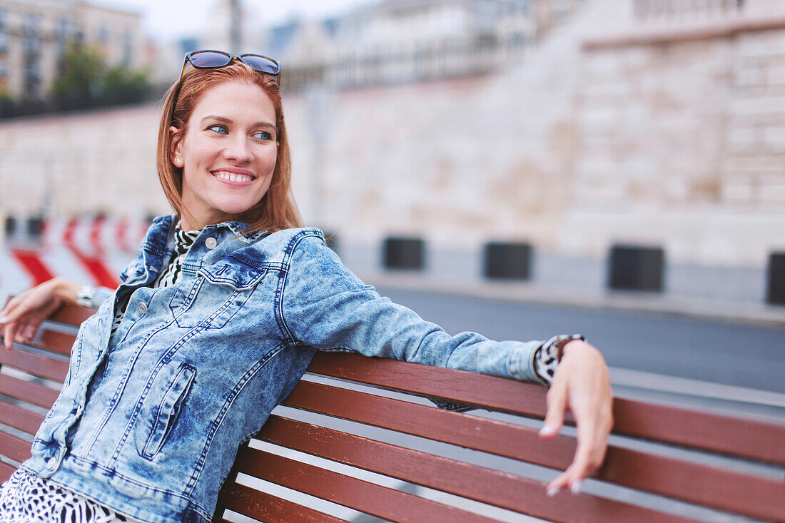 Happy young woman sitting on bench
