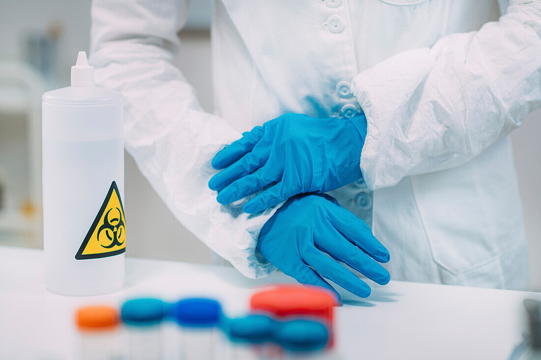 Lab technician putting on protective clothing