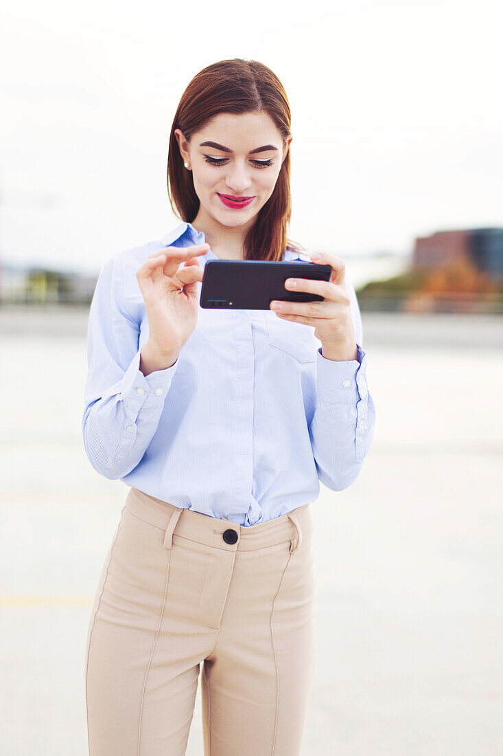 Young businesswoman with smartphone outdoors