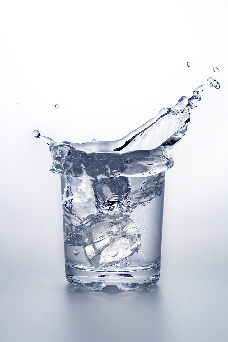 Ice cube splashing into glass of water