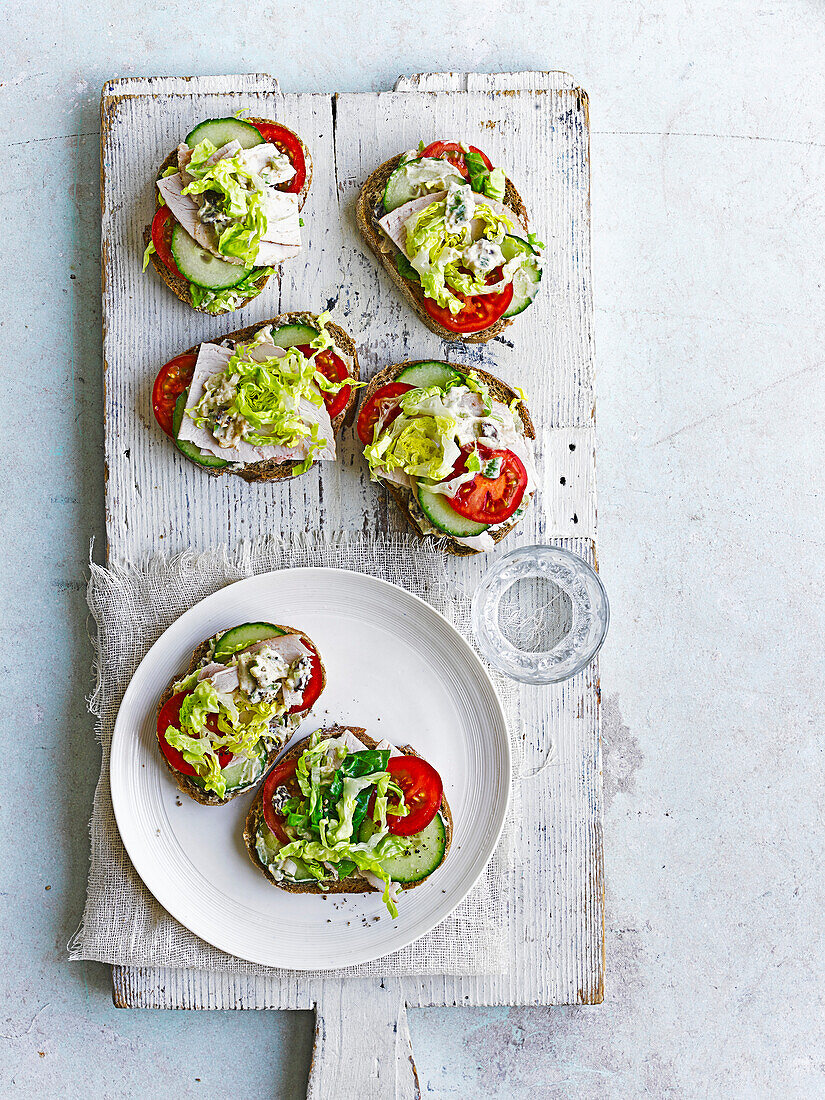 Slices of rye bread topped with tomatoes, turkey breast, cucumber and lettuce