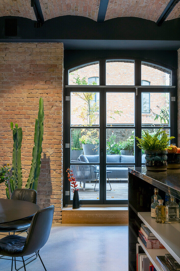 Loft living room with cactus next to window front and terrace access