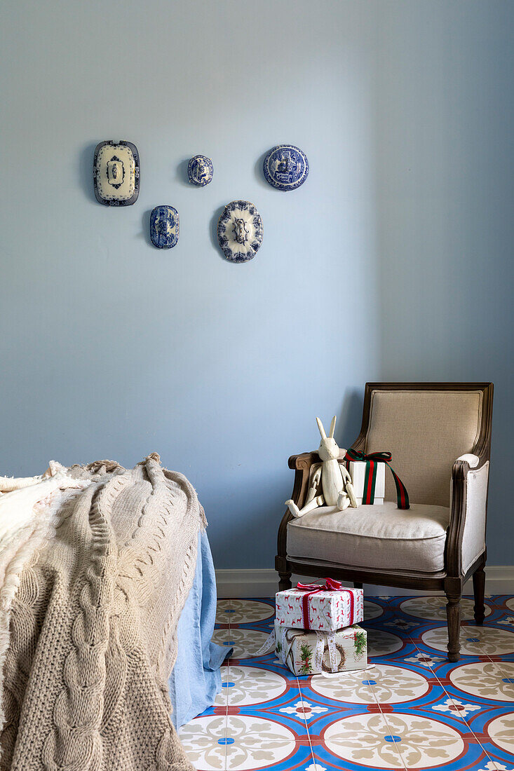 Armchair, presents, bed, light blue walls and patterned tiled floor in bedroom