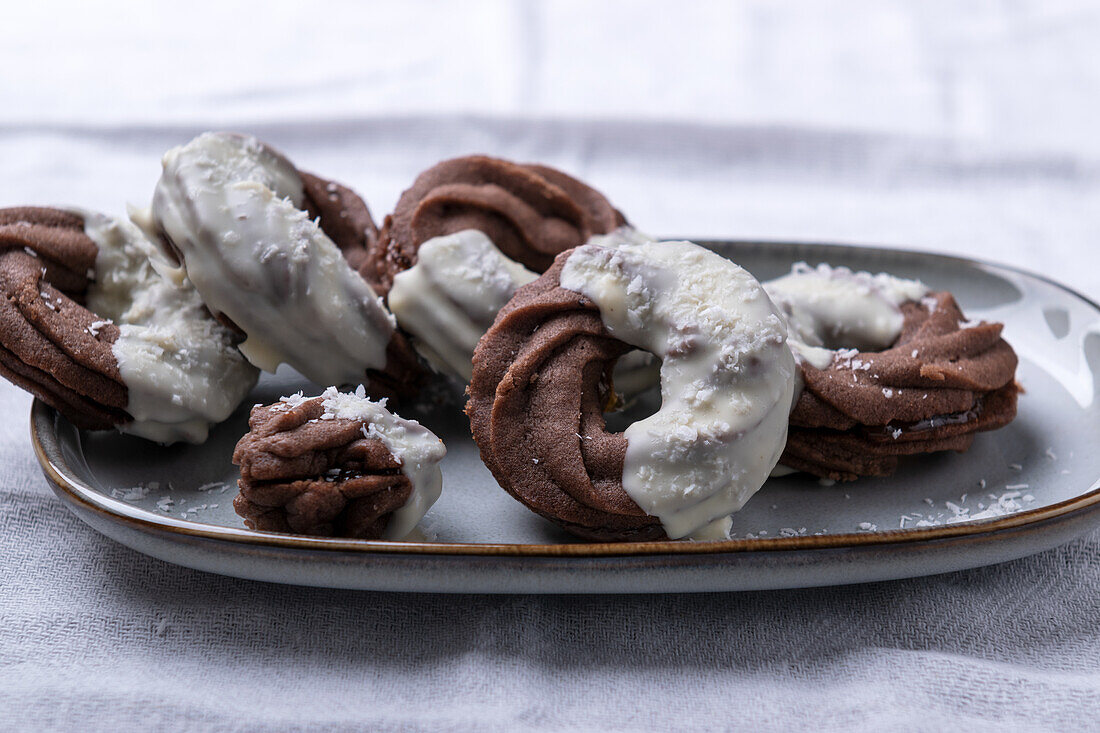 Vegan chocolate piped cookies filled with jam, covered with white rice milk chocolate