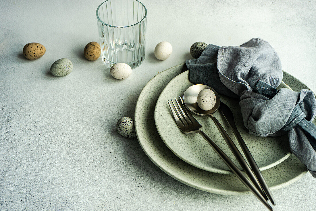 Place setting for Easter festive dinner with eggs on concrete background