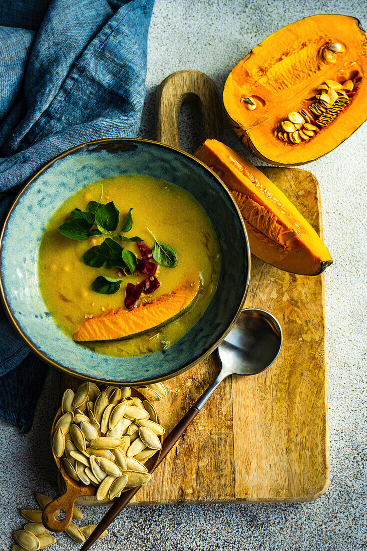 Healthy pumpkin soup served in blue ceramic bowl on stone background