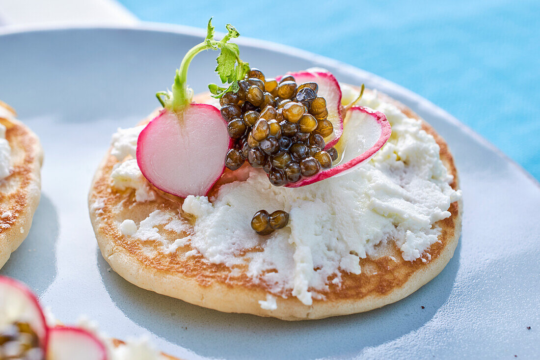 A blini topped with goat's cream cheese, radishes and caviar