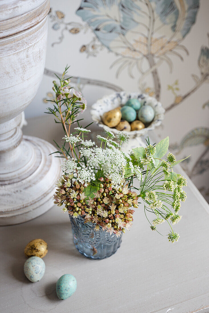 Small bouquet of flowers and decorative eggs on bedside table