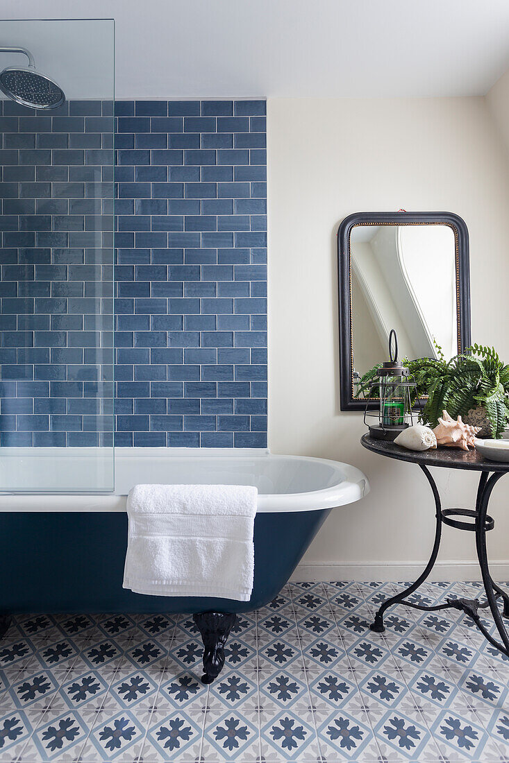 Freestanding bath and round table in a bathroom with patterned floor tiles