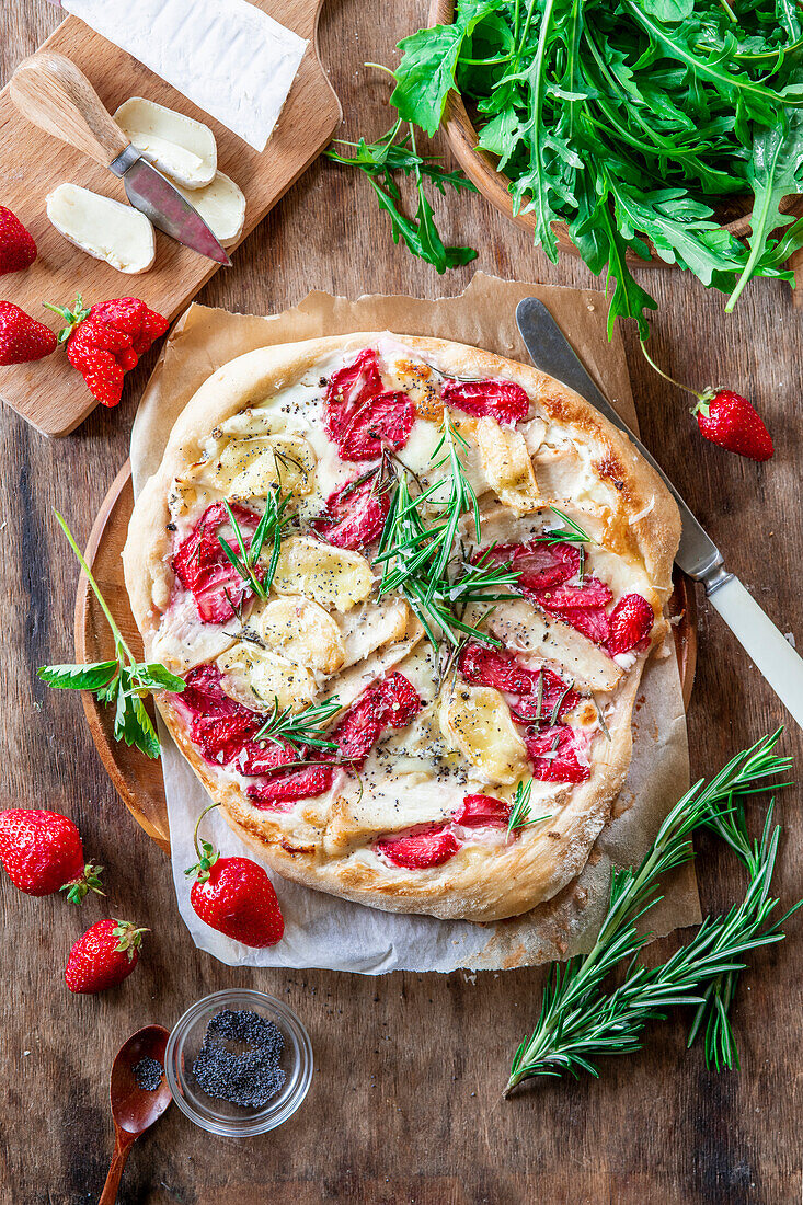 Strawberry pizza with chicken fillet, brie cheese, poppy seeds, rosemary and rocket salad