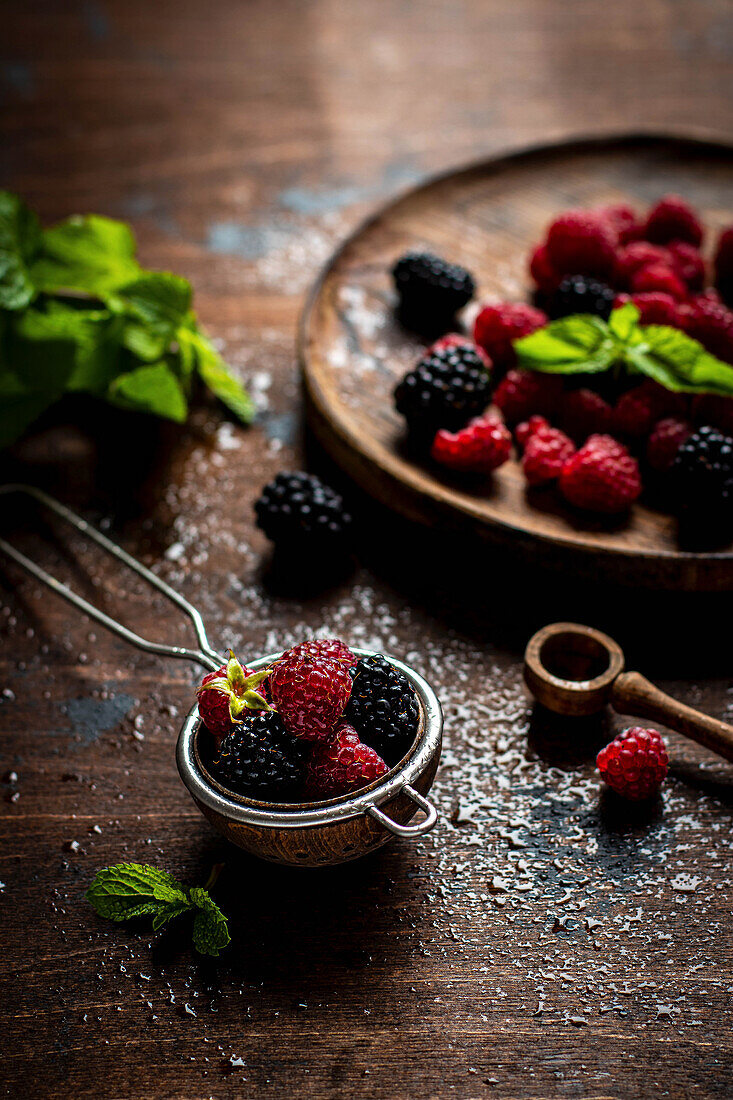 Fresh berries in a sieve and on a wooden plate