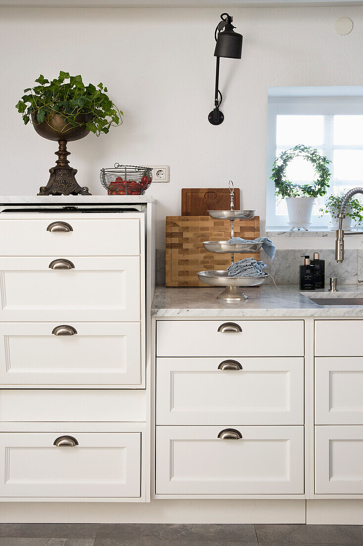 White kitchen unit with marble top, black wall mounted light above it