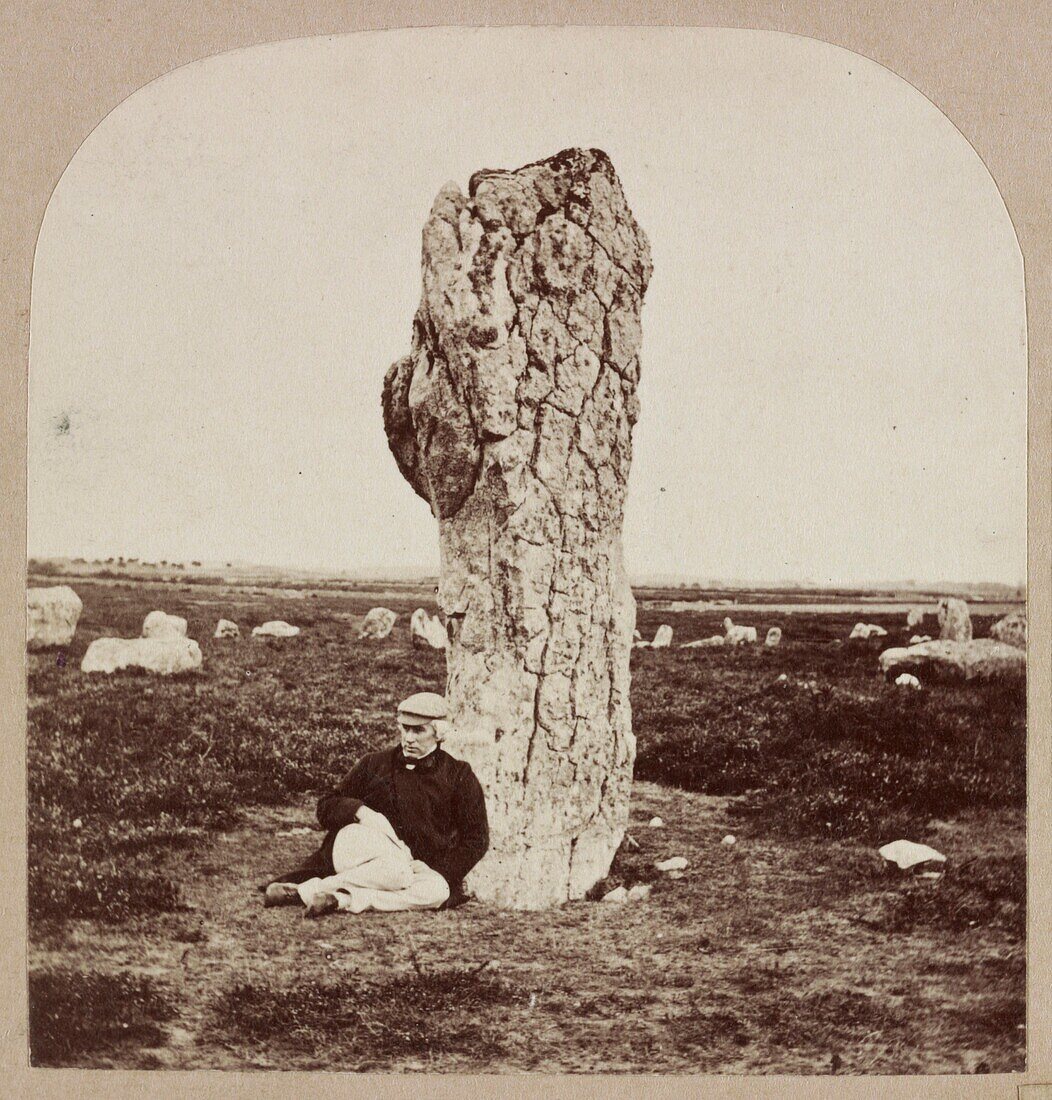 Man sitting below a standing stone, Menec, France