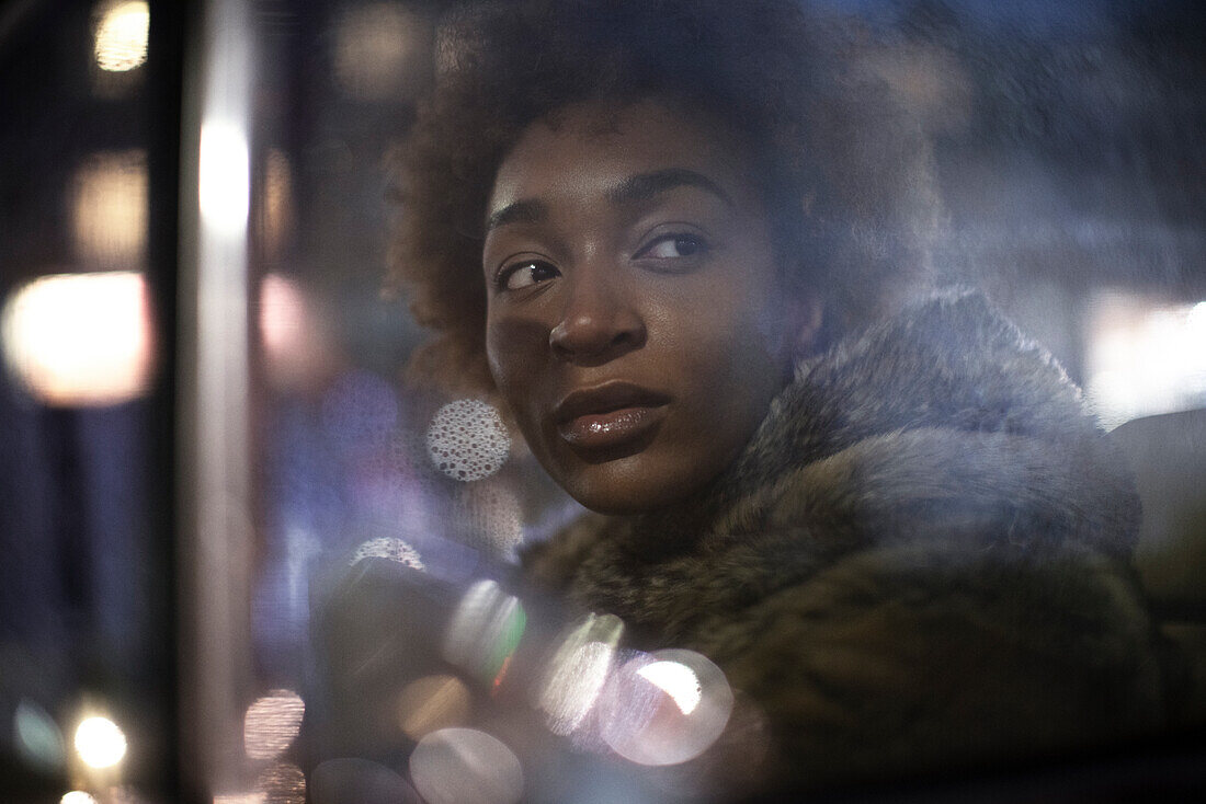 Young woman looking out car window at night