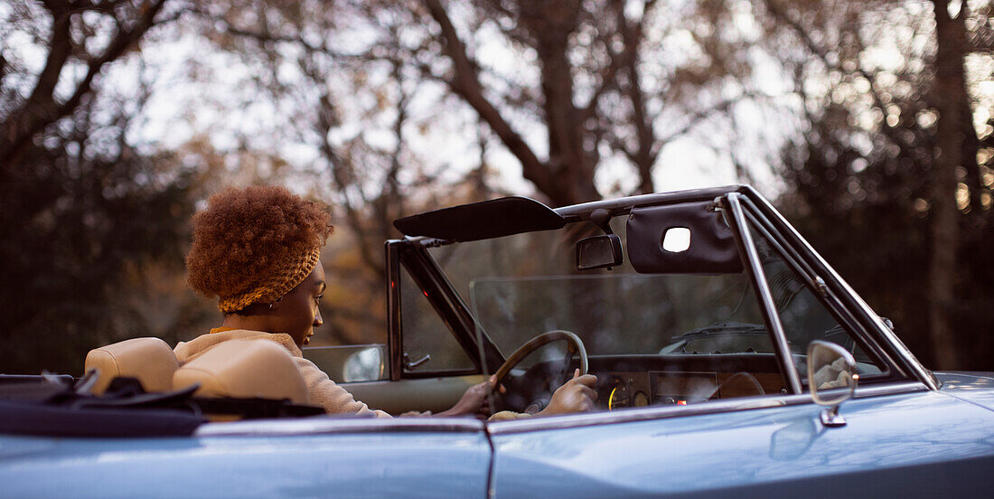 Young woman driving convertible in park