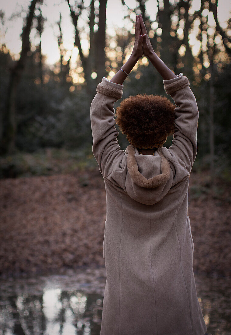 Young woman with hands clasped overhead in park