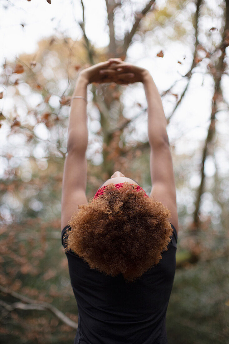 Young woman stretching arms overhead in park