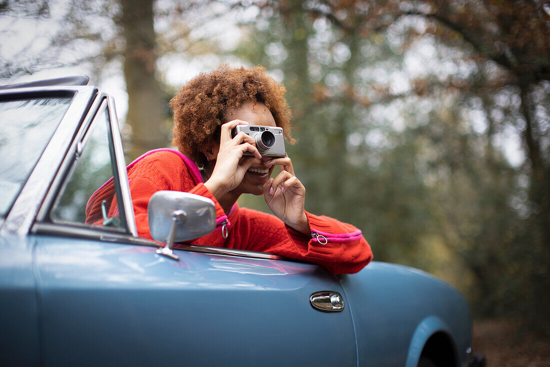 Young woman using digital camera in convertible