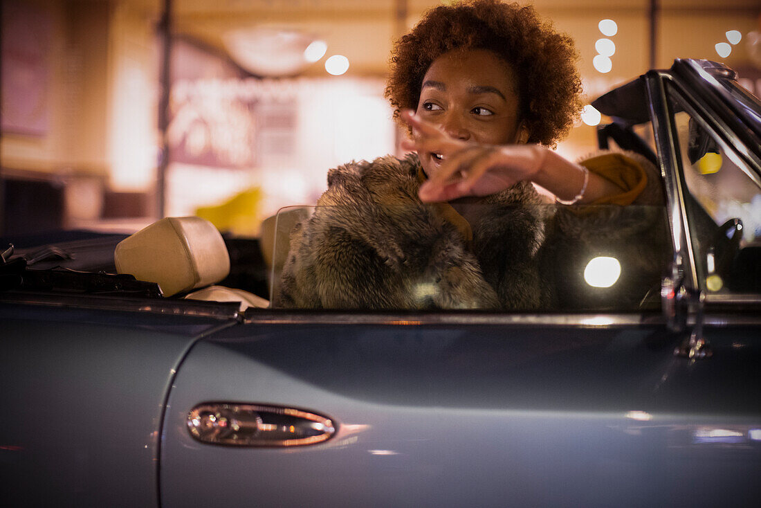 Young woman in convertible at night
