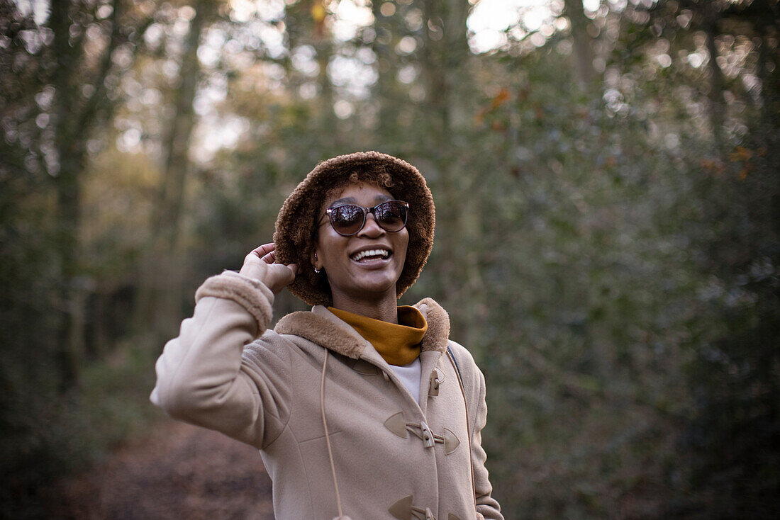 Carefree young woman in hat and sunglasses in park