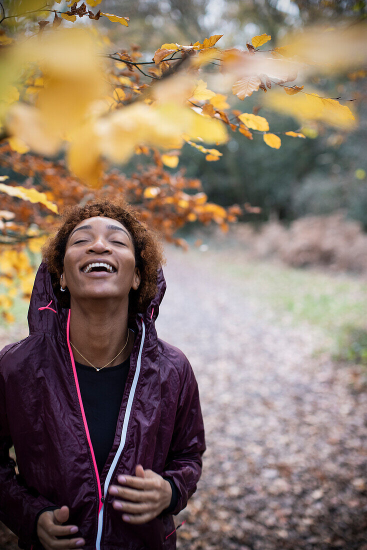 Happy young female runner in autumn woods