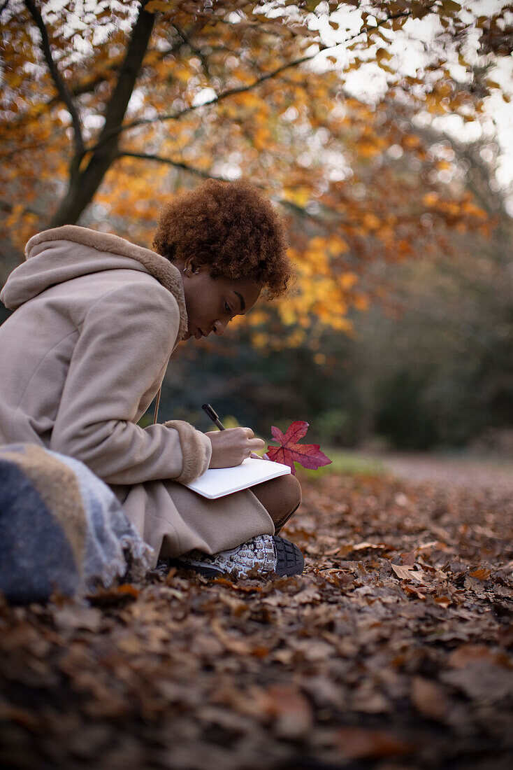Young woman journaling in autumn leaves
