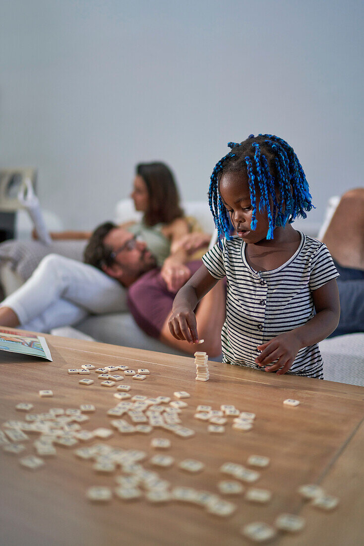 Toddler girl stacking scrabble tiles on coffee table