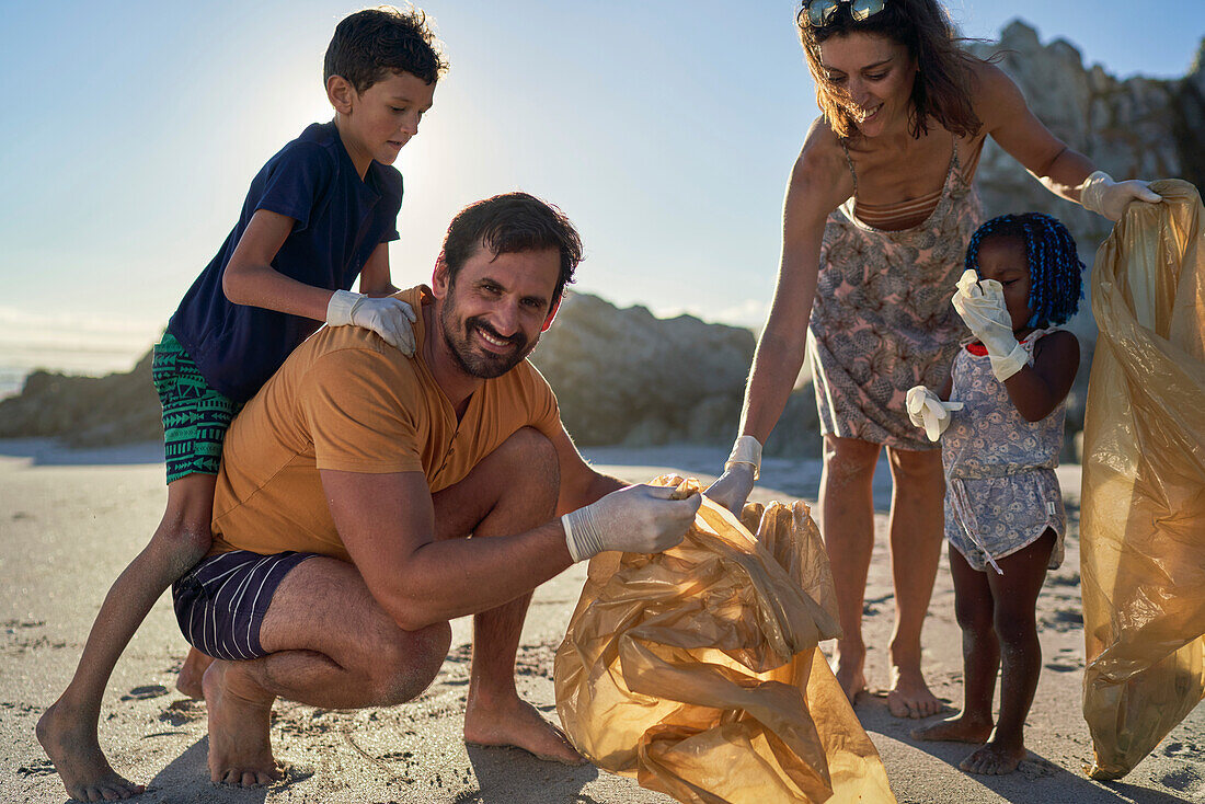 Happy family picking up garbage on sunny beach