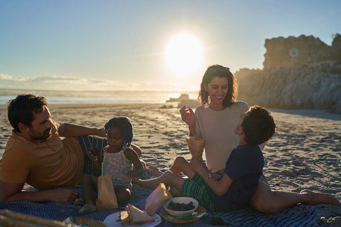 Happy family enjoying picnic on sunny summer beach