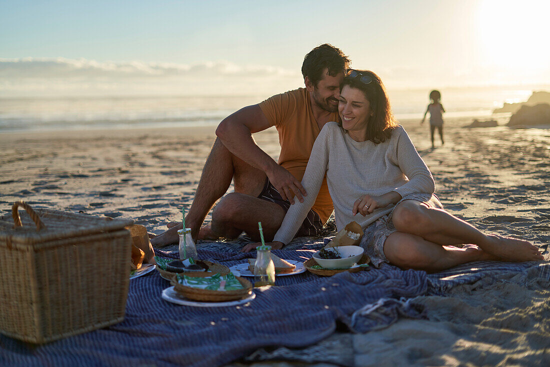 Happy affectionate couple enjoying picnic on summer beach