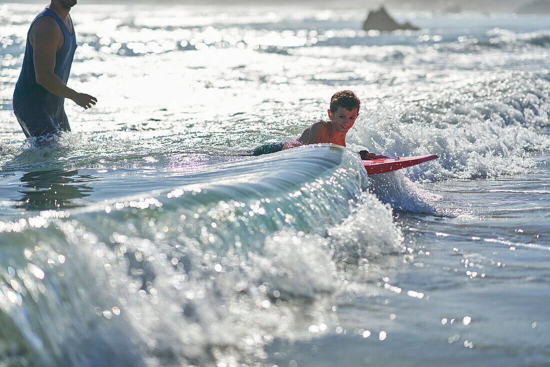 Happy boy body boarding in sunny ocean surf