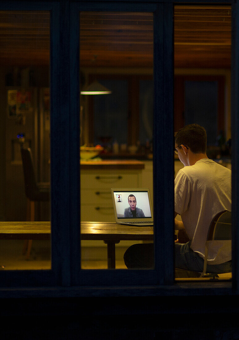 Man working late video conferencing with colleagues