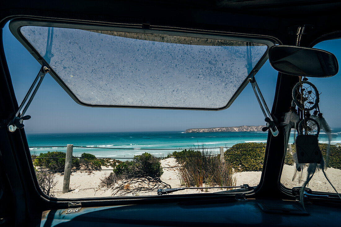 Bus window open to sunny ocean seascape