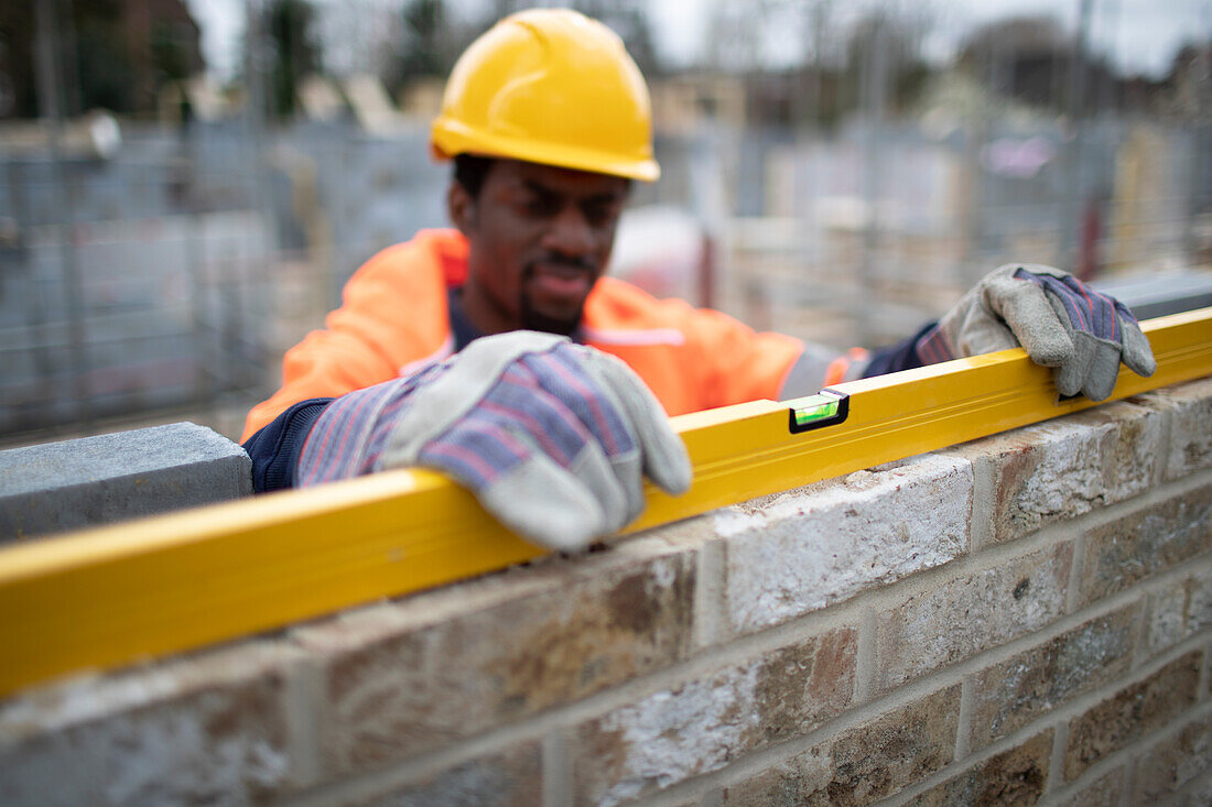 Construction worker using level tool on brick wall
