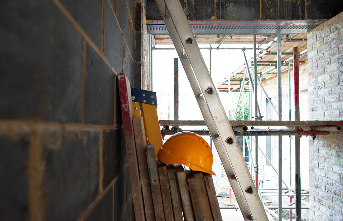 Hard hat, wood planks and ladders at construction site