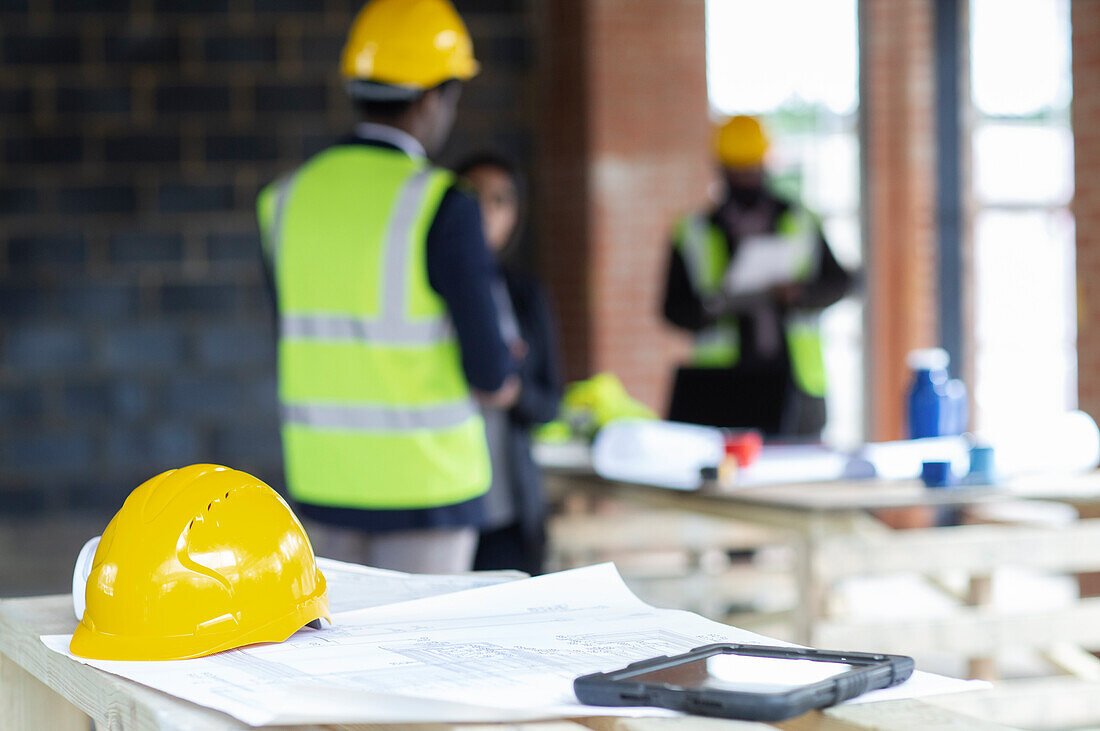 Hard hat and digital tablet on blueprints