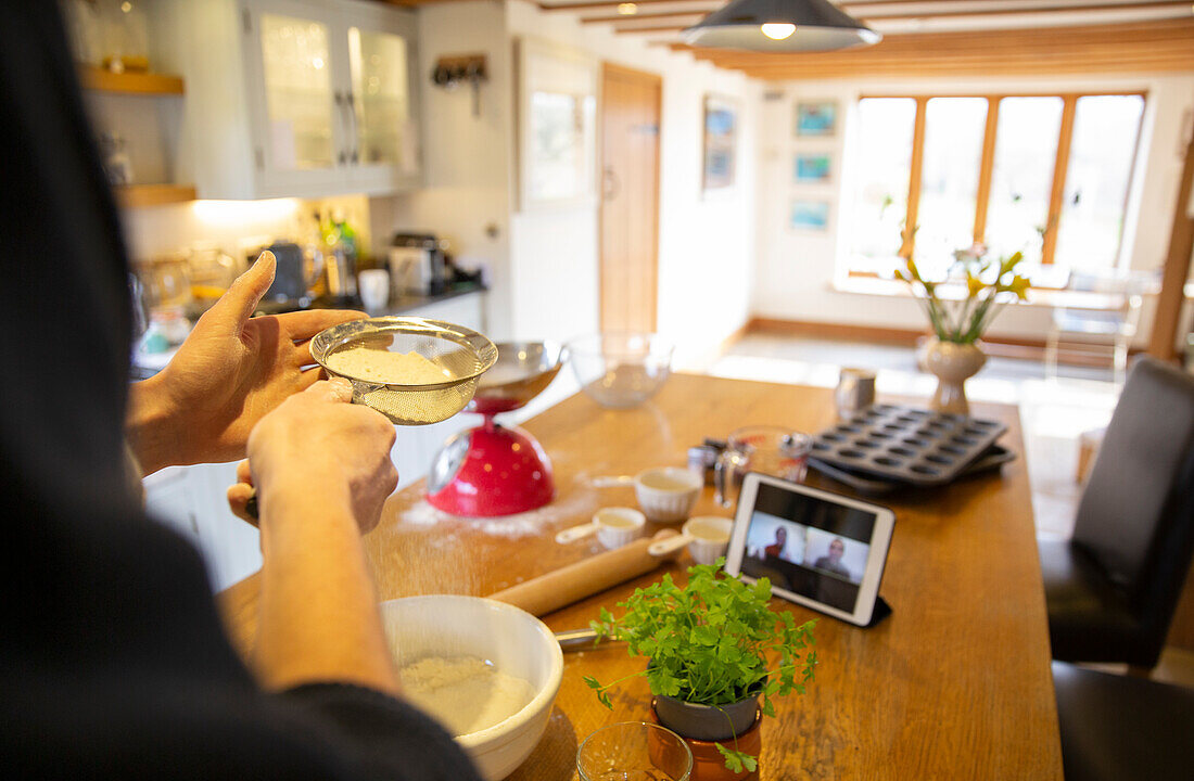 Man video chatting and making fresh pizza dough in kitchen