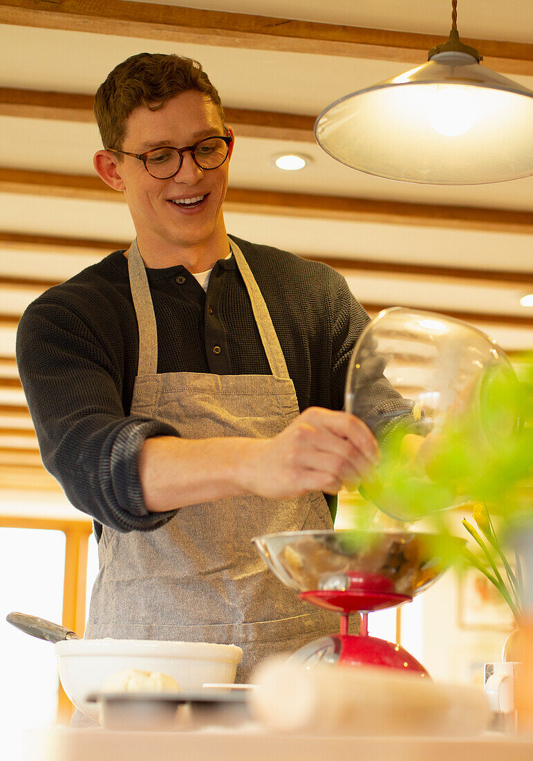 Smiling man baking using scale in kitchen