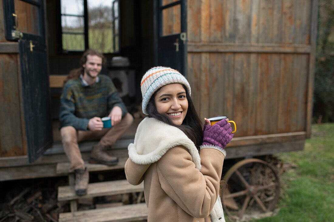 Happy young couple enjoying coffee outside tiny cabin rental