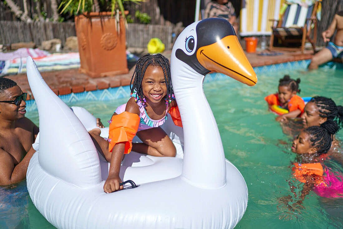 Girl on inflatable swan in summer swimming pool