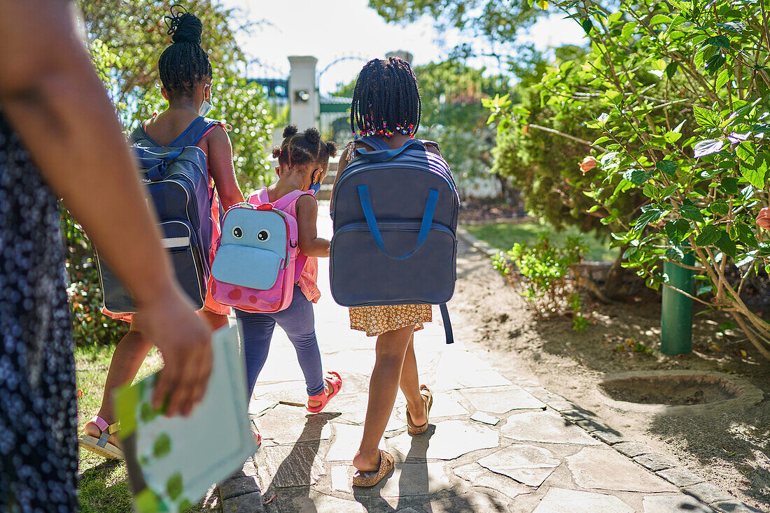 Sisters with backpacks walking on sunny summer footpath