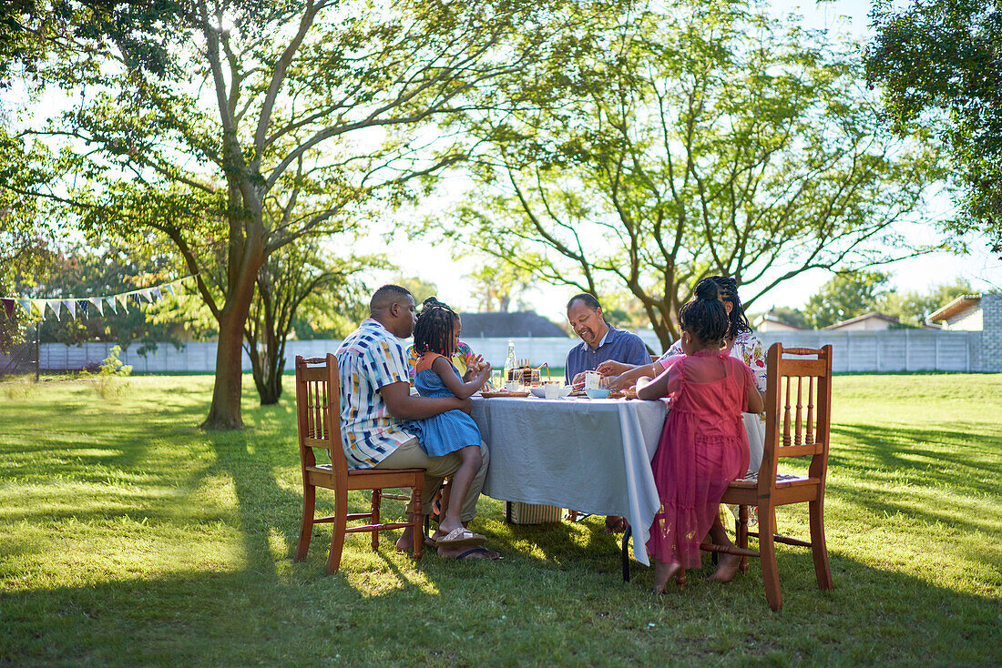 Multigenerational family enjoying lunch at table in backyard